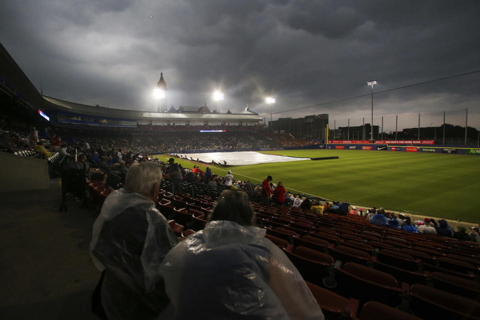 Fans watch as the grounds crew covers the infield with a tarp before the baseball game between the Toronto Blue Jays and Boston Red Sox on Tuesday, July 20, 2021, in Buffalo, N.Y. The game was postponed due to a thunderstorm in the area. (AP Photo/Joshua Bessex)