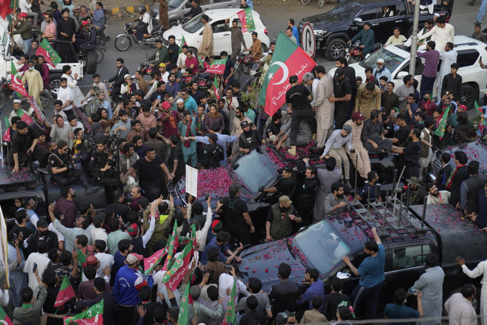 Security personnels and supporters move with a vehicle, center, carrying Pakistan's former Prime Minister Imran Khan during an election campaign rally, in Lahore, Pakistan, Monday, March 13, 2023. Khan rallied thousands of supporters in eastern Pakistan on Monday as courts in the capital, Islamabad, issued two more arrest warrants for him over his failure to appear before judges in graft and terrorism cases, officials said. (AP Photo/K.M. Chaudary)