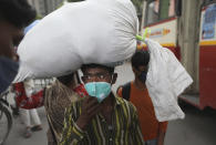 A Migrant worker arrives at a bus station to leave for his village following a six-day lockdown put into place to control the rising cases of coronavirus infections, in New Delhi, India, Tuesday, April 20, 2021. India recorded over 250,000 new infections and over 1,700 deaths in the past 24 hours alone, and the U.K. announced a travel ban on most visitors from the country this week. (AP Photo/Manish Swarup)