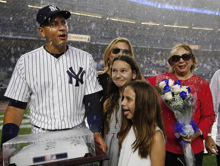 Alex Rodriguez and family leave the field amid a sudden thunderstorm during his pre-game ceremony at Yankee Stadium. (AP)