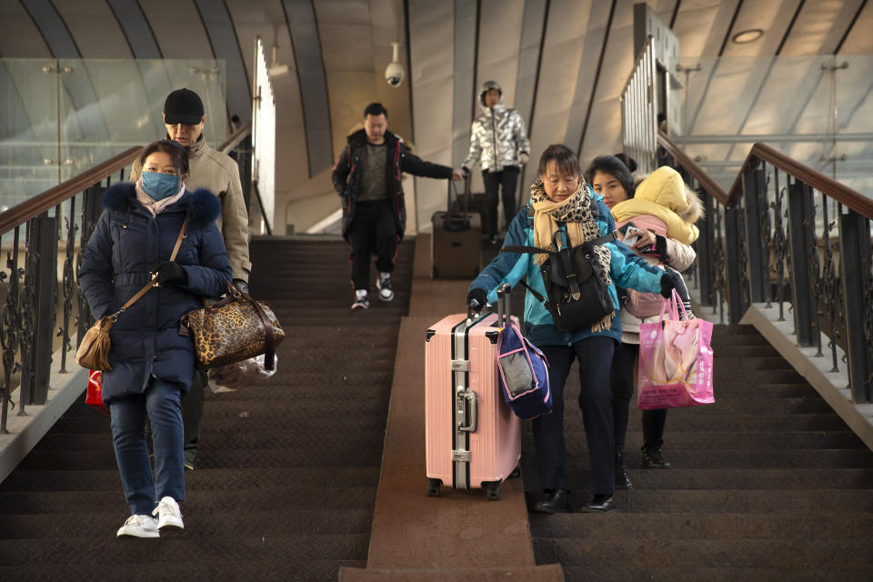 Travelers prepare to board their train at the Beijing Railway Station in Beijing, Friday, Jan. 17, 2020. As the Lunar New Year approached, Chinese travelers flocked to train stations and airports Friday to take part in a nationwide ritual: the world's biggest annual human migration. (AP Photo/Mark Schiefelbein)