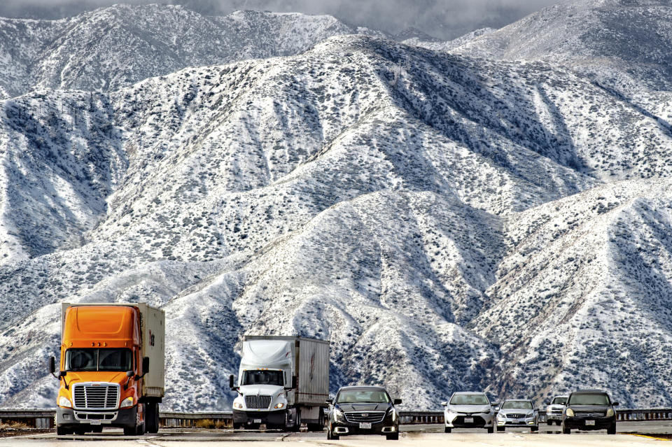 Mountains are blanketed with snow as traffic makes its way slowly through Cajon Pass on the I-15 near Hwy 138 in Phelan, Calif., Thursday, Feb. 21, 2019. (Watchara Phomicinda/The Orange County Register via AP)