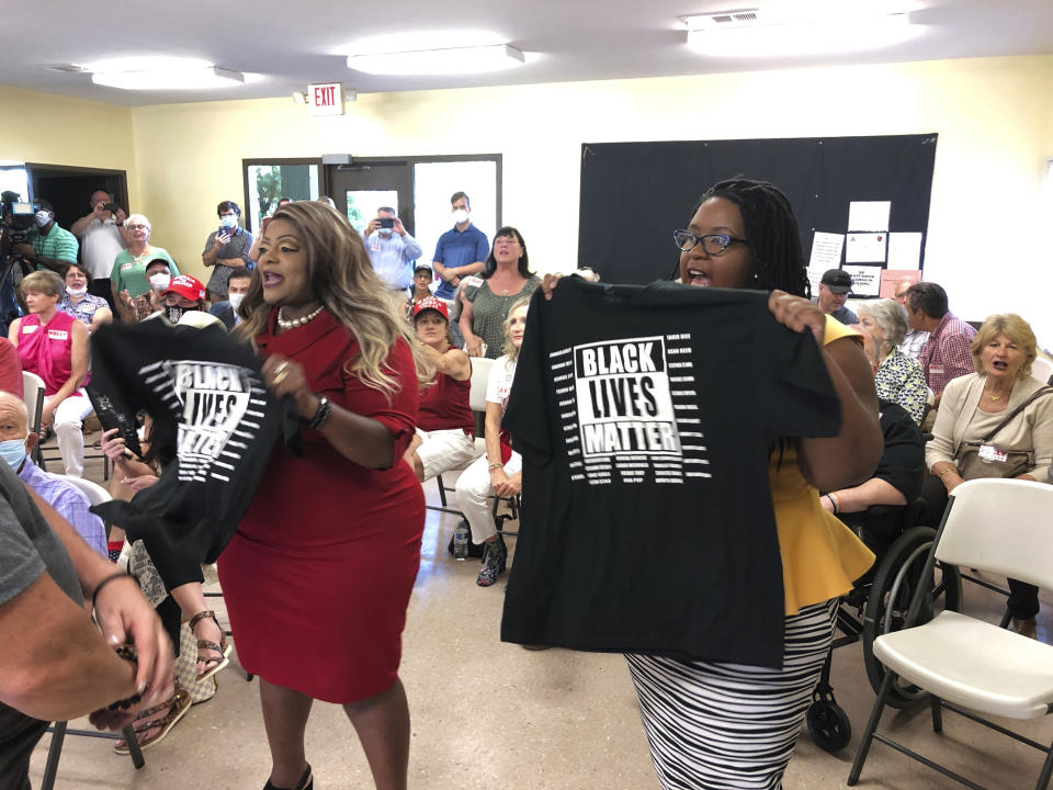 CORRECTS LAST NAME TO JAMES, NOT GAINES - Triana Arnold James, left, and Nselaa Ward hold up Black Lives Matter T-shirts as they protest a speech by U.S. Sen. Kelly Loeffler, Thursday, Sept 3, 2020, in Cumming, Ga. James and Ward kept Loeffler from finishing a campaign speech. (AP Photo/Jeff Amy)