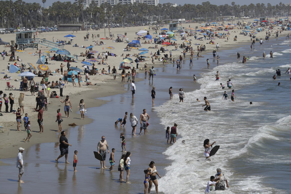 FILE - In this July 12, 2020, file photo, visitors crowd the beach in Santa Monica, Calif., amid the coronavirus pandemic. As states around the country require visitors from areas with high rates of coronavirus infections to quarantine upon arrival, children taking end-of-summer vacations to hot spots are facing the possibility of being forced to skip the start of in-person learning at their schools. (AP Photo/Marcio Jose Sanchez, File)