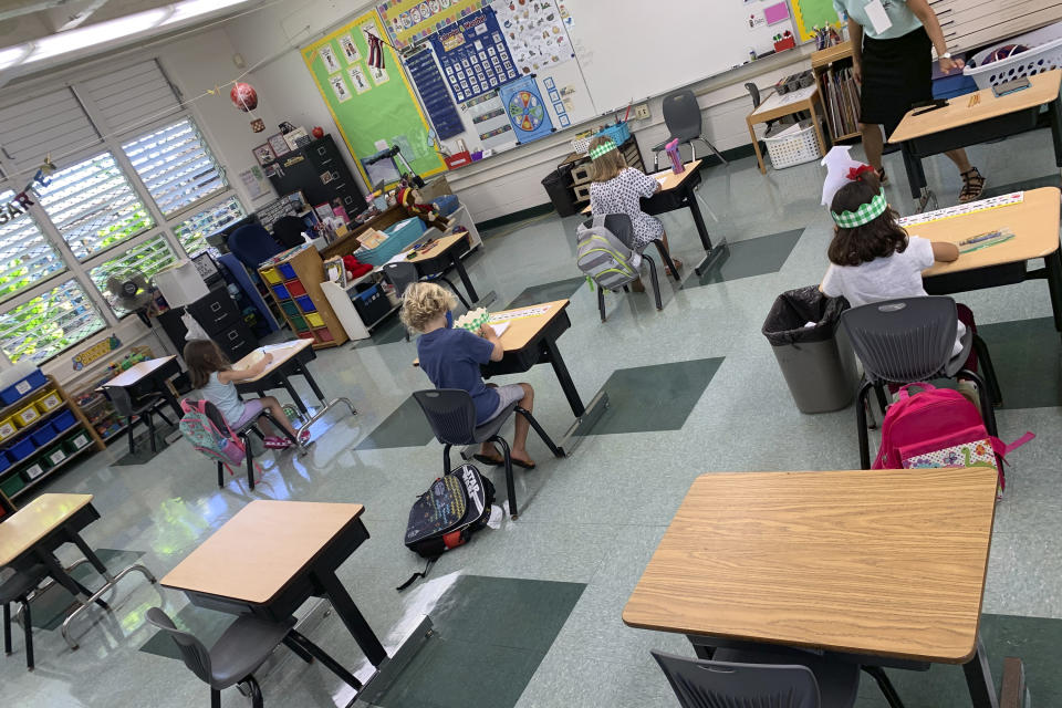 In this photo provided by Keoki Fraser, a small group of kindergarteners sits spaced apart in a classroom at Aikahi Elementary School in Kailua, Hawaii on Monday, Aug. 17, 2020. The teachers union is concerned many students are going to campuses despite announcements from education officials that Hawaii public schools would be starting the first four weeks online. Aikahi Principal Keoki Fraser says small groups of students are coming in this week for a few hours at a time for orientation, learning how to use technology for remote learning, and to connect with teachers and friends. (Keoki Fraser via AP)