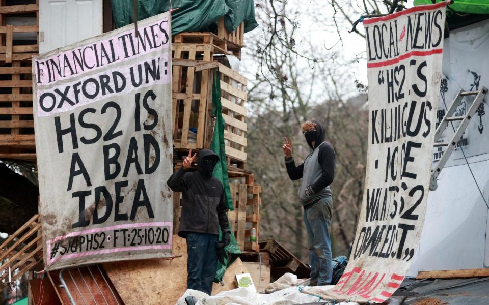 Extinction Rebellion activists gesture next to signs at a makeshift camp as part of an HS2 protest - Reuters