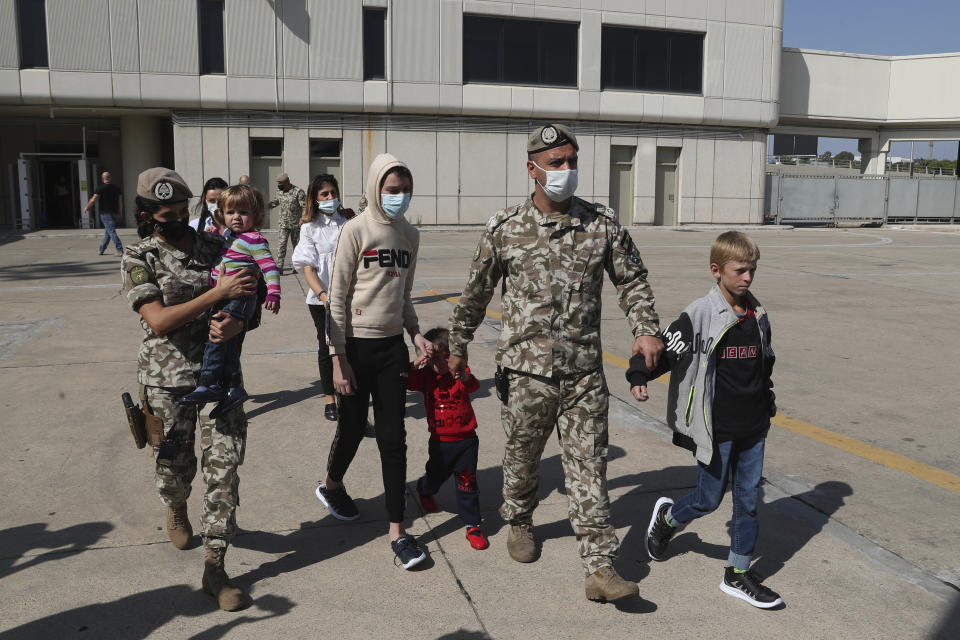 Members of the Lebanese General Security forces walk with Albanian children during an operation to take them back home to Albania from al-Hol, northern Syria, at the Rafik Hariri International Airport in Beirut, Lebanon, Tuesday, Oct. 27, 2020. The repatriation of four children and a woman related to Albanian nationals who joined Islamic extremist groups in Syria "is a great step" to be followed by more repatriations, Albania's prime minister said Tuesday in Beirut. (AP Photo/Bilal Hussein)