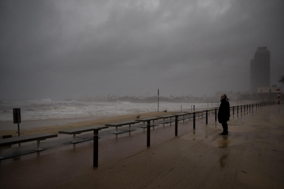 A man looks at the Mediterranean sea during a storm in Barcelona, Spain, Tuesday, Jan. 21, 2020. A winter storm lashed much of Spain for a third day Tuesday, leaving 200,000 people without electricity, schools closed and roads blocked by snow as it killed four people. Massive waves and gale-force winds smashed into seafront towns, damaging many shops and restaurants. (AP Photo/Emilio Morenatti)