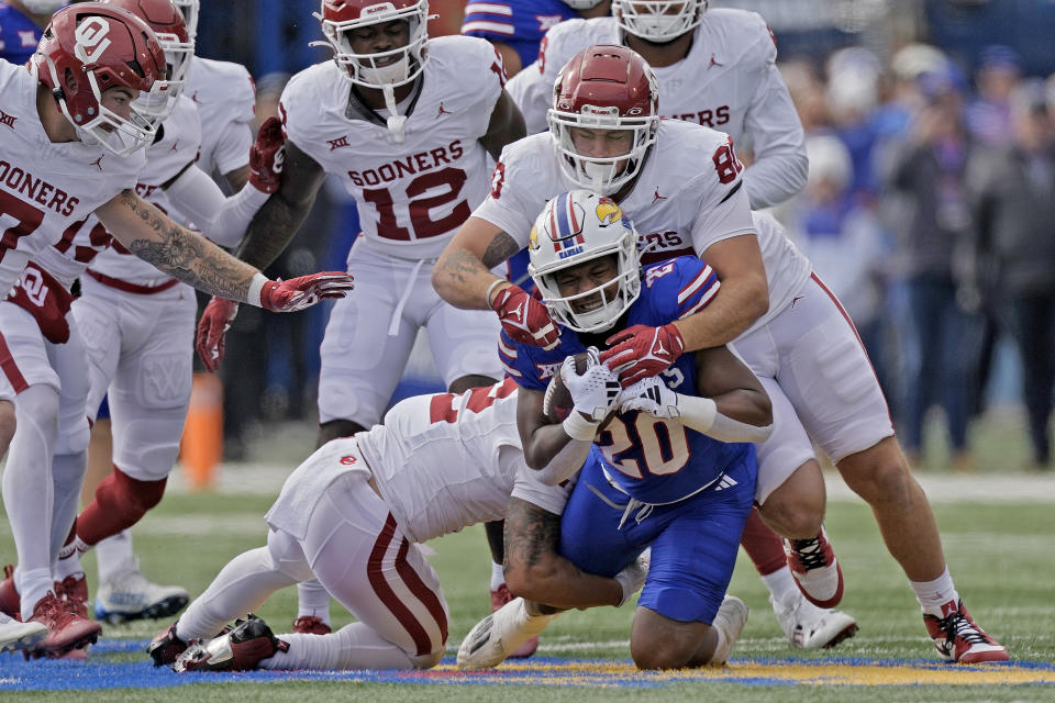 Kansas running back Daniel Hishaw Jr. (20) is tackled by Oklahoma defensive lineman Rondell Bothroyd (80) as he runs for a first down during the first half of an NCAA college football game Saturday, Oct. 28, 2023, in Lawrence, Kan. (AP Photo/Charlie Riedel)