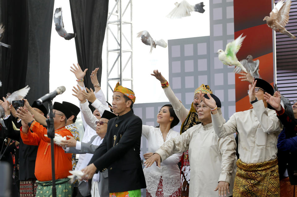 Indonesian President Joko Widodo, second left, and his running mate Ma'ruf Amin, left, and his contender Prabowo Subianto, second right, with his running mate Sandiaga Uno, right, release birds during a ceremony marking the kick off of the campaign period for next year's election in Jakarta, Indonesia, Sunday, Sept. 23, 2018. Indonesia is set to hold its presidential and parliamentary election poll in April 2019.(AP Photo/Tatan Syuflana)