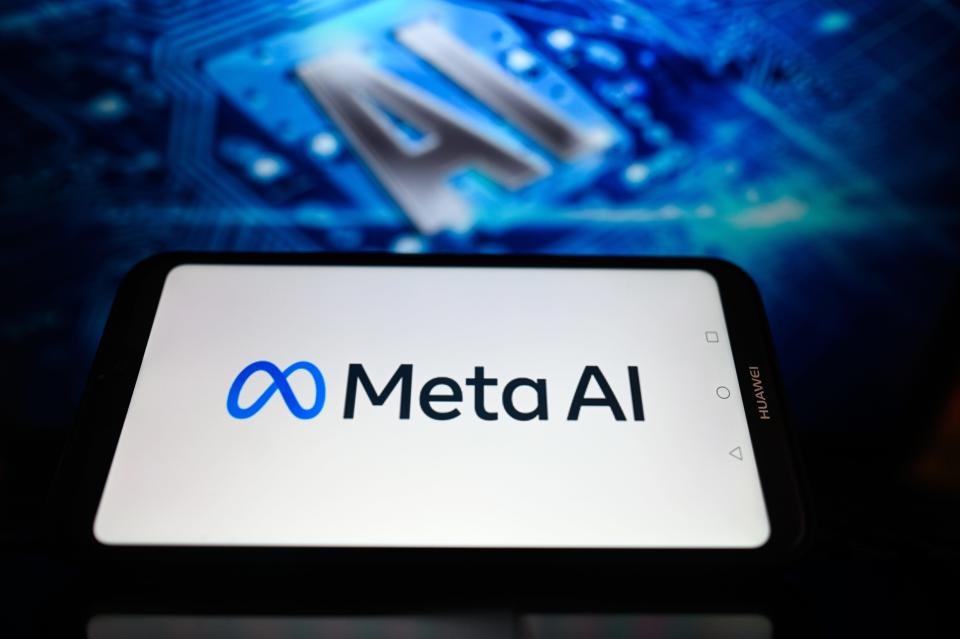 Meta logo displayed on a phone in front of a graphic that says AI