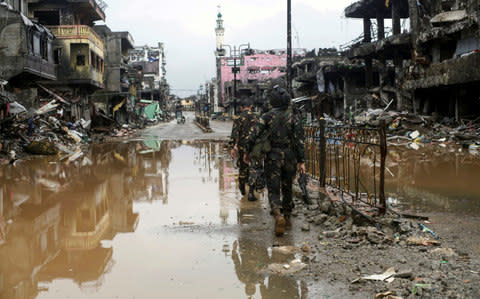 Government troops pass destroyed buldings and houses in Datu Sa Dansalan in Marawi city, southern Philippines - Credit:  REUTERS