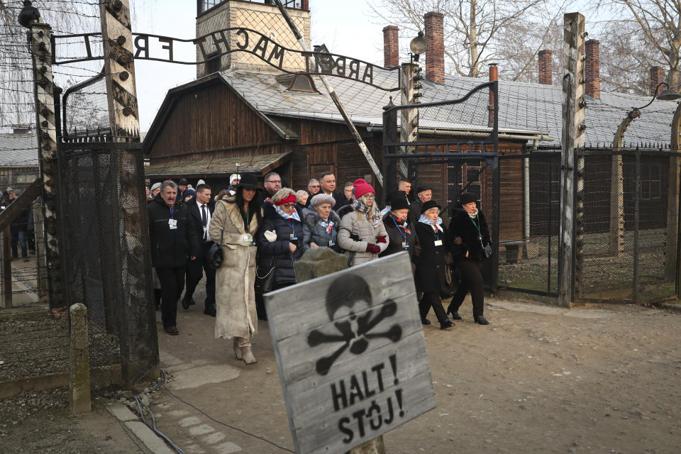 Poland's president Andrzej Duda walks with survivors through the main gate of the camp.