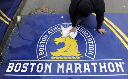 Alex Herrera cleans a portion of the finish line before the start of the 119th running of the Boston Marathon in Boston, Massachusetts April 20, 2015. REUTERS/Gretchen Ertl