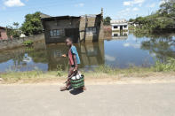 A young boy walks past a house submerged in water caused by Cyclone Idai in Inchope, Mozambique, Monday March 25, 2019. Cyclone Idai's death toll has risen above 750 in the three southern African countries hit 10 days ago by the storm, as workers rush to restore electricity, water and try to prevent outbreak of cholera. (AP Photo/Tsvangirayi Mukwazhi)
