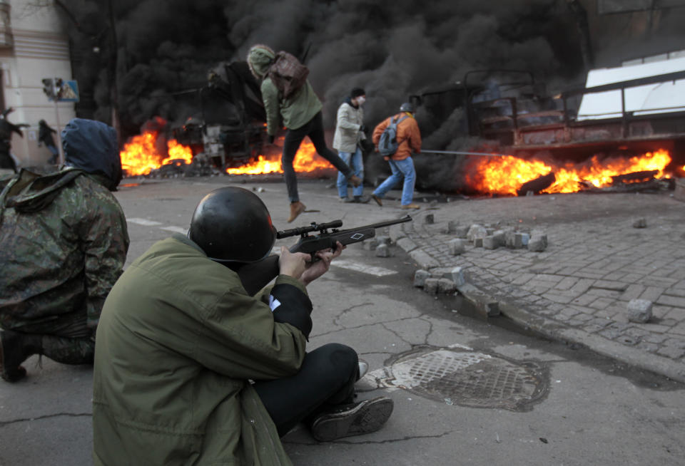 FILE - In this file photo taken on Tuesday, Feb. 18, 2014, an anti-government protester shoots during clashes with riot police outside Ukraine's parliament in Kiev, Ukraine. A former Soviet republic on the fault line between Russia and Europe is boiling with revolt this summer. Sounds familiar — but Belarus 2020 isn’t Ukraine 2014, and that’s why it’s hard to predict what will happen next. (AP Photo/Sergei Chuzavkov, File)