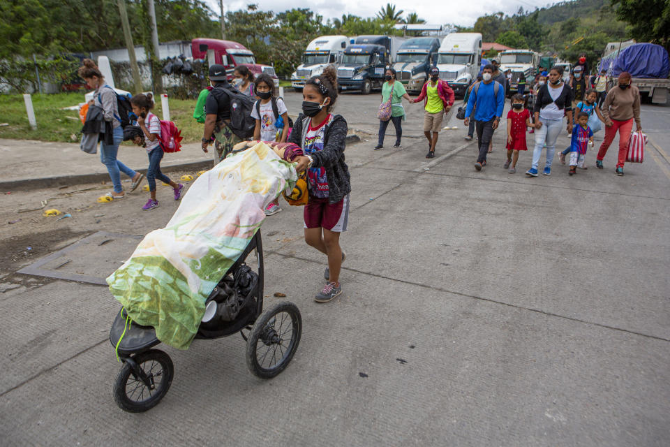 Honduran migrants walk to the border crossing after being transported in an army truck to El Florido, Guatemala, a border point between Guatemala and Honduras, Tuesday, Jan. 19, 2021. A once large caravan of Honduran migrants that pushed its way into Guatemala last week had dissipated by Tuesday in the face of Guatemalan security forces. (AP Photo/Oliver de Ros) 03104