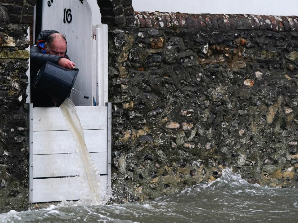 A person bails water from a property as sea water floods the shore line in Hampshire (PA)