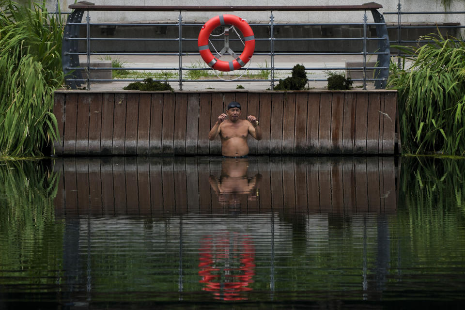 A man prepares to swim as he cool off from a hot day in Beijing, Monday, July 3, 2023. Heavy flooding has displaced thousands of people around China as the capital had a brief respite from sweltering heat. Beijing reported 9.8 straight days when the temperature exceeded 35 C (95 F), the National Climate Center said Monday. (AP Photo/Andy Wong)