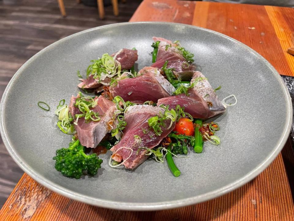 Hito Yatai’s katsuo tataki features sliced bonito with crunchy broccolini, tomatoes and a tangy chili crisp.