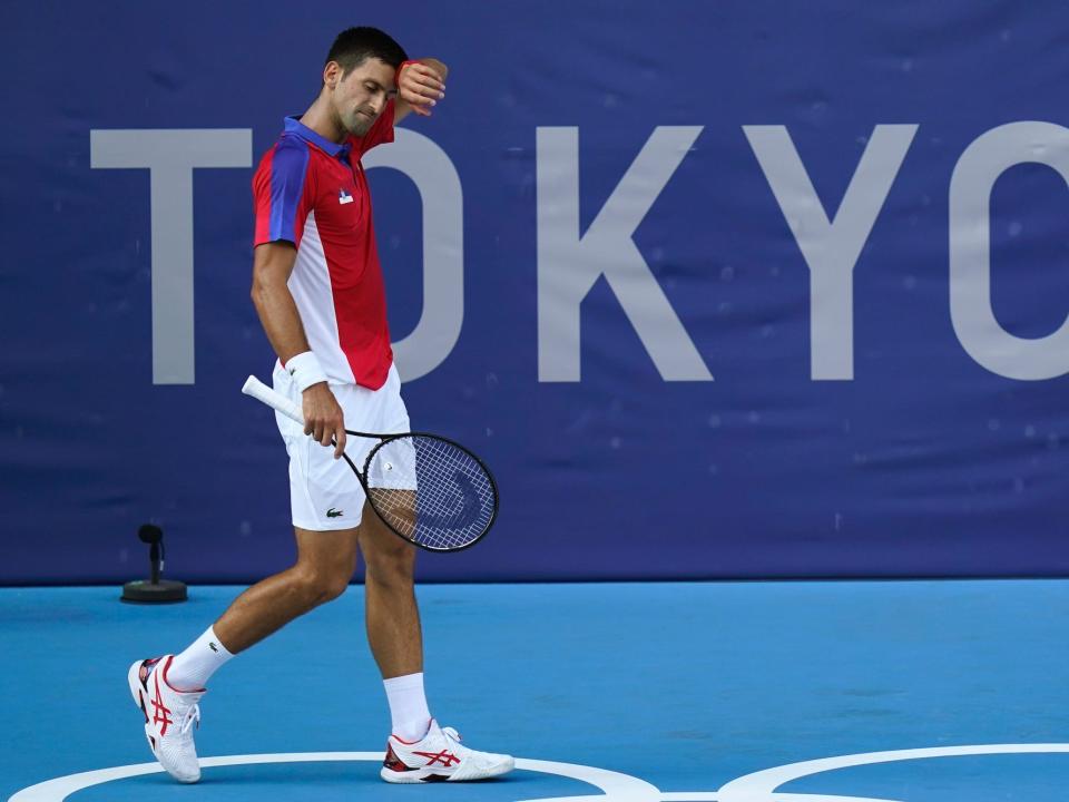 Novak Djokovic wipes sweat off his face during a match at the Tokyo Olympics.