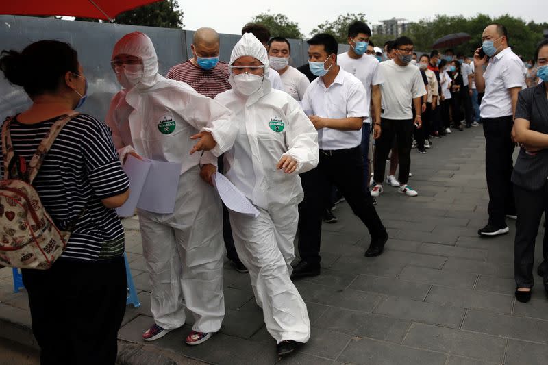 Medical workers attend to people lining up outside a site for nucleic acid tests in Beijing