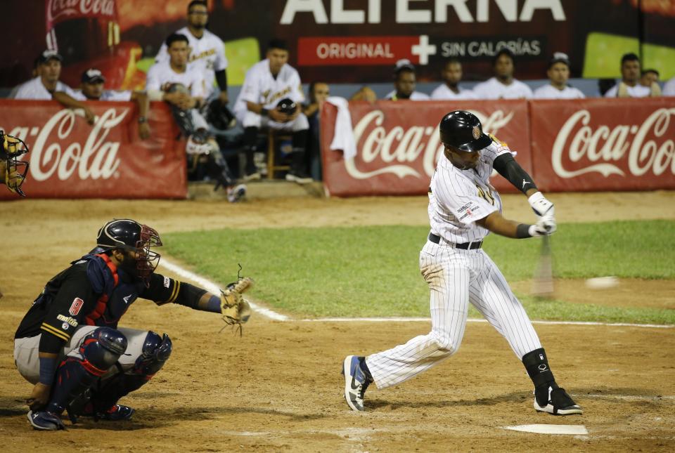 A Leones de Caracas player hits the ball during the opening winter season game with Tigres de Aragua in Caracas, Venezuela, Tuesday, Nov. 5, 2019. Over the years, Venezuela’s winter league drew athletes like Bob Gibson, Barry Bonds and Pete Rose, but many fans said this year major league players were noticeably absent. (AP Photo/Ariana Cubillos)