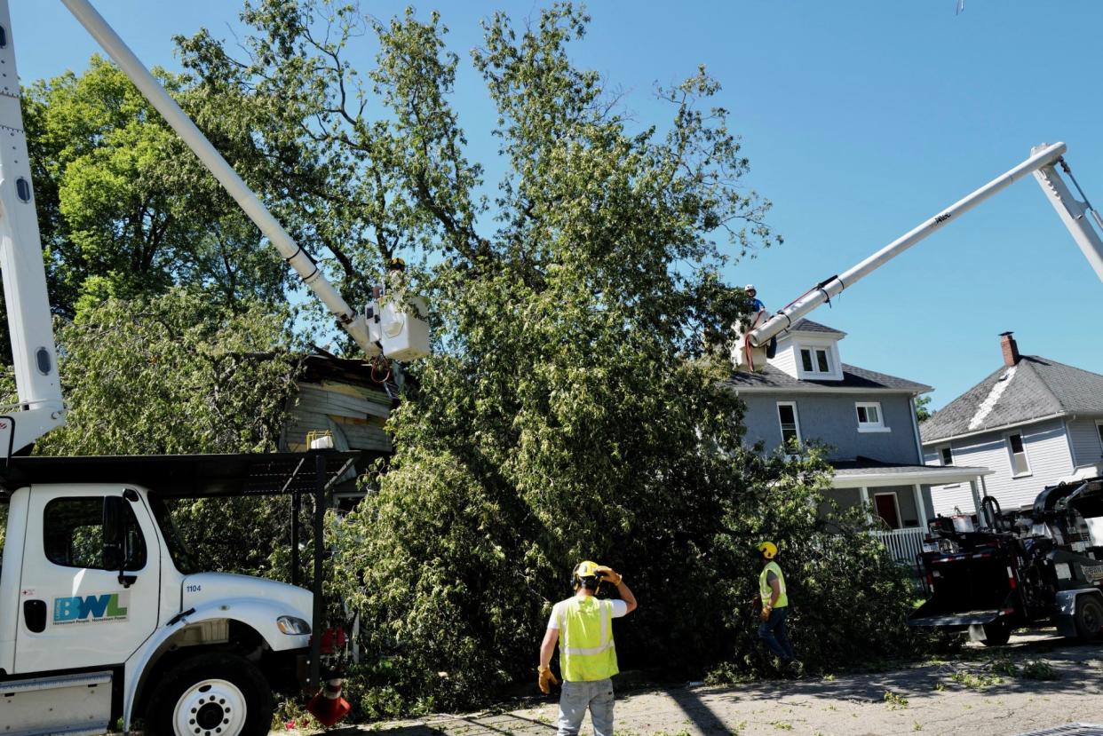 BWL workers begin to cut limbs of the large hickory tree that fell on the house of Vernita Payne during last Thursday’s major storm, killing her.