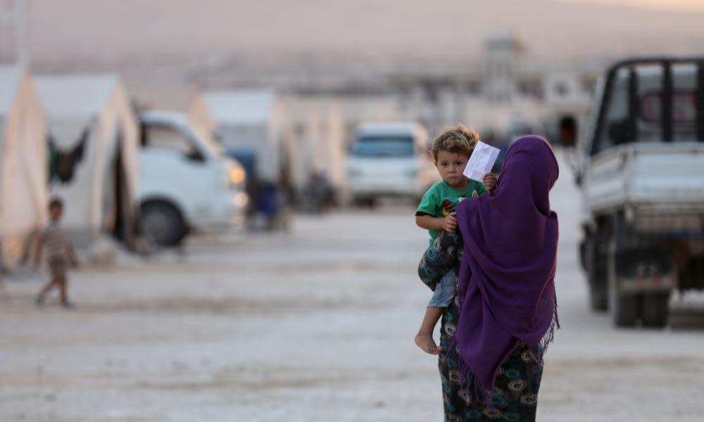 A displaced Syrian woman holds a toddler in a camp in Kafaldin. The US will reduce the number of refugees entering by a third.