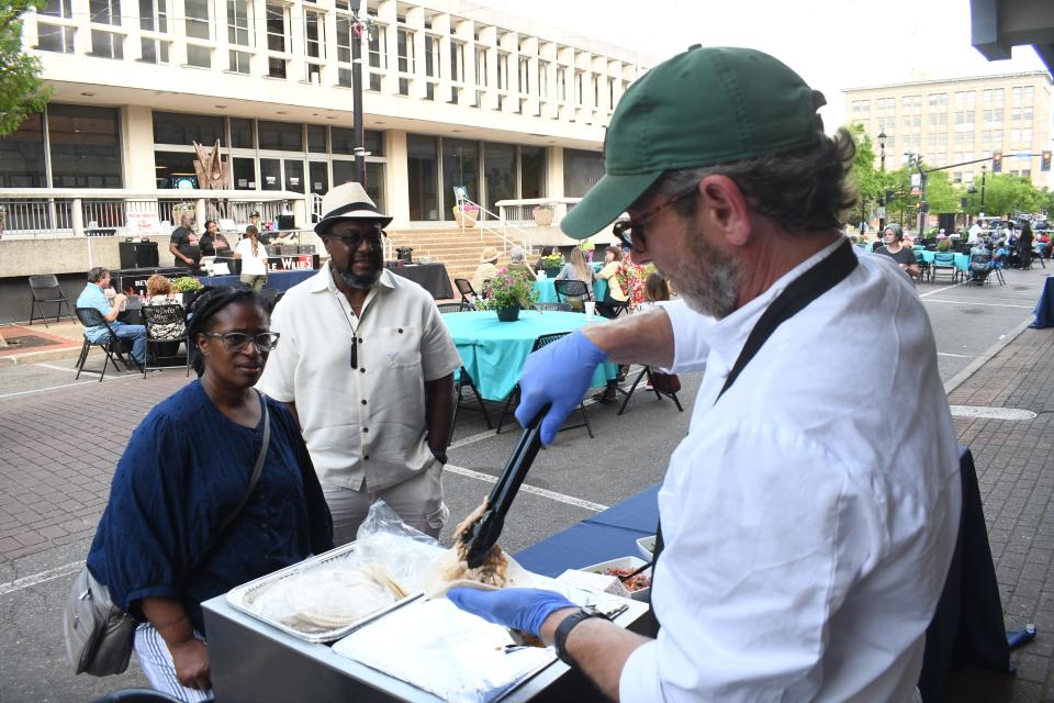 Delsey and John Thomas watch Brad Blackwood, owner of Cafe Desoto, make a Roasted Chicken Taco with Homemade Salsa and Chipolte Cream at Dinner on the Bricks held Thursday on Third Street.