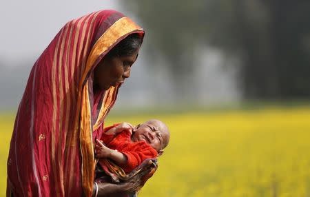 Monowara holds her 22-day-old grandson Arafat, as she walks through a mustard field on the outskirts of Dhaka January 22, 2014. REUTERS/Andrew Biraj