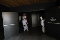 Workers wait for the end of a film to disinfect a theater after a movie screening, at the Cineteca Nacional, Mexico's film archive, in Mexico City, Wednesday, Aug. 12, 2020. After being closed for nearly five months amidst the ongoing coronavirus pandemic, movie theaters in the capital reopened Wednesday at 30% capacity.(AP Photo/Rebecca Blackwell)