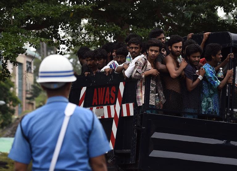 A member of the Malaysian Navy stands guard as a truck carrying Bangladeshi and Rohingya migrants from a temporary detention centre arrives at a naval base in Langkawi on May 13, 2015