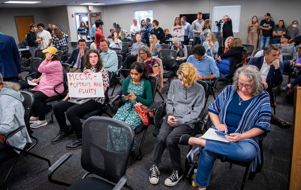 Bloomington High School South student Lillith Roberts holds a sign against the proposed schedule changes during Tuesday's school board meeting. Of about 120 people who attended, about one-third were students.