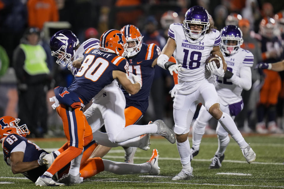 Northwestern defensive back Garner Wallace (18) recovers a fumble by Illinois before running in a touchdown during the second half of an NCAA college football game Saturday, Nov. 25, 2023, in Champaign, Ill. (AP Photo/Erin Hooley)