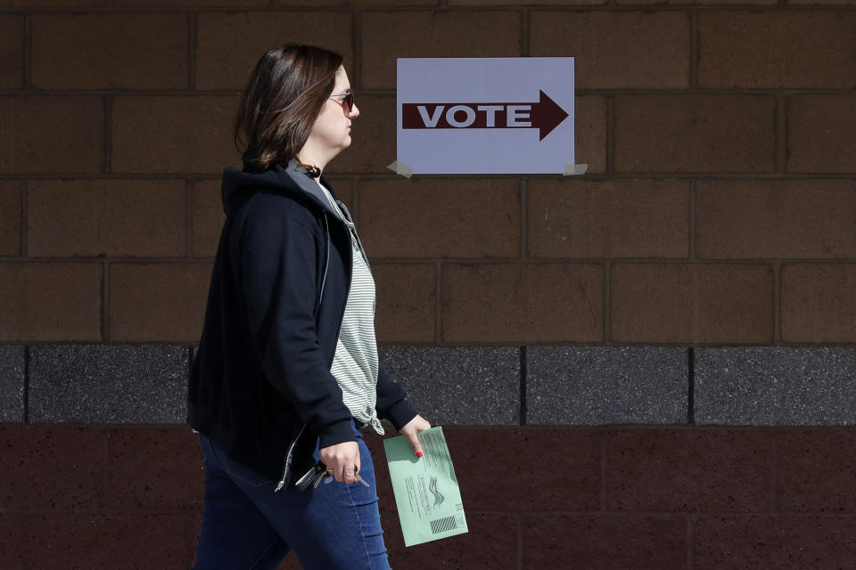 An Arizona voter delivers her mail-in ballot at a polling station for the Arizona presidential preference election Tuesday, March 17, 2020, in Phoenix. (AP Photo/Matt York)