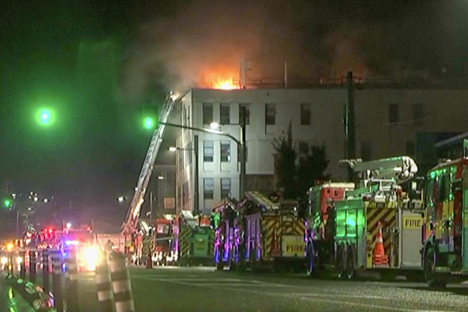 In this image made from video, firetrucks stage outside a hostel in central Wellington, New Zealand, early Tuesday, May 16, 2023. Several people were killed after a fire broke out overnight at the four-story building. (NewsHub via AP)