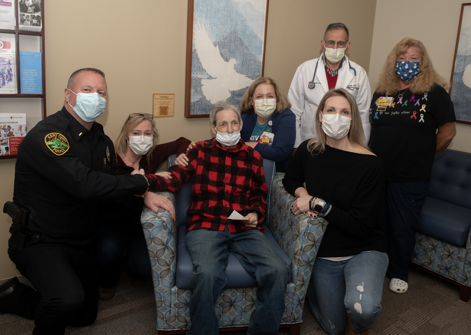 Sitting, from left, Kent Police Lt. Mike Lewis, Denise Ficzeri and her uncle Carl Fike, Kent dispatcher Rebecca Schneider, registered nurse Laura Vargo, and standing, Dr. Saif Rehman and registered nurse Kathy Korman. Fike is holding a $500 check he received from the Kent Police Department through a program to help local cancer patients.