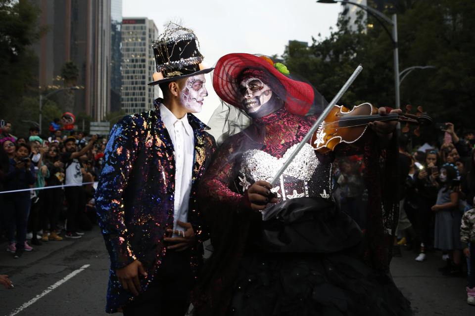 A couple dressed as Catrinas parade down Mexico City's iconic Reforma avenue during celebrations for the Day of the Dead in Mexico, City, Saturday, Oct. 26, 2019. (AP Photo/Ginnette Riquelme)