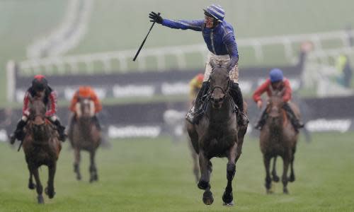 A jockey raises one hand in celebration