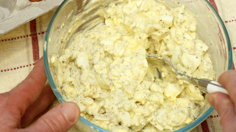 Person mixing bowl of egg salad