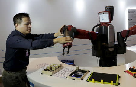 A staff member sets up the position of a mechanical hand for a Baxter robot of Rethink Robotics, during a display at the World Economic Forum (WEF), in China's port city Dalian, Liaoning province, China, September 9, 2015. REUTERS/Jason Lee