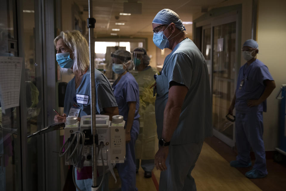 FILE - In this July 7, 2020, file photo, Nurse Cindy Kelbert, left, checks on a critically ill COVID-19 patient through a glass door as she is surrounded by other nurses at St. Jude Medical Center in Fullerton, Calif. The U.S. death toll from COVID-19 has almost topped 500,000 — a number so staggering that a top health researchers says it is hard to imagine an American who hasn't lost a relative or doesn't know someone who died. (AP Photo/Jae C. Hong)