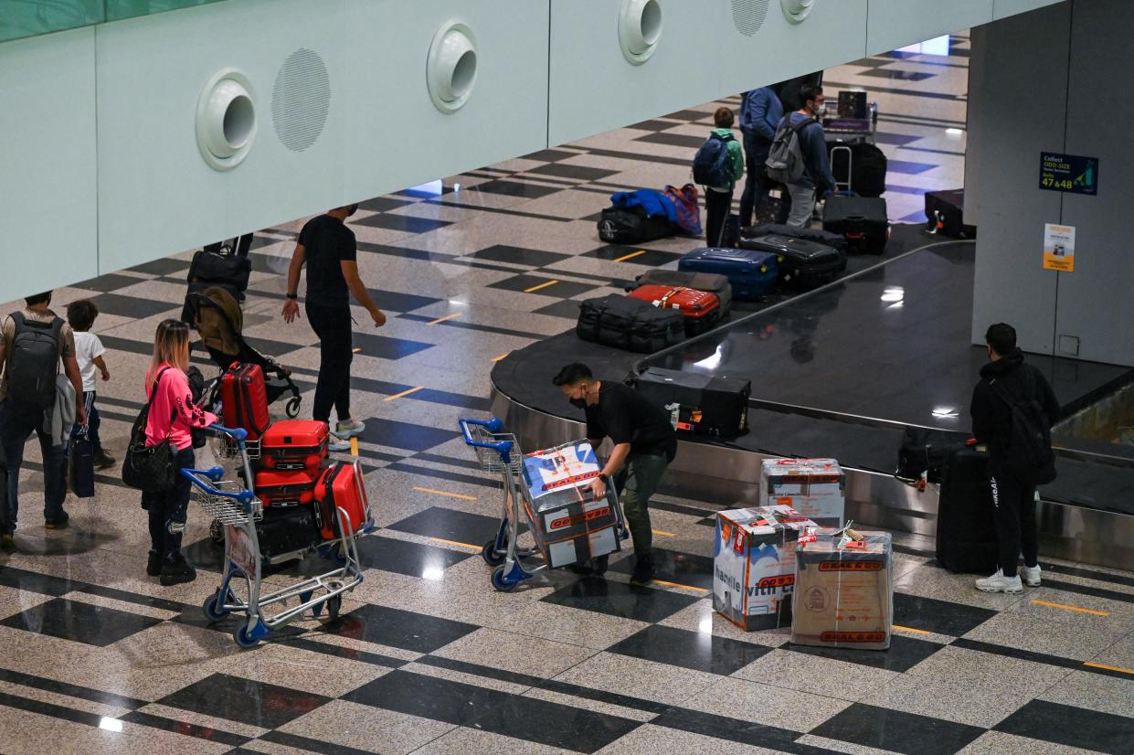 Passengers arriving from Amsterdam get their bags at Changi Airport in Singapore on October 20, 2021, a day after the country began quarantine-free entry for fully vaccinated passengers from eight countries, part of a plan to ease restrictions as the business hub gears up to live with the coronavirus. (Photo by Roslan RAHMAN / AFP) (Photo by ROSLAN RAHMAN/AFP via Getty Images)