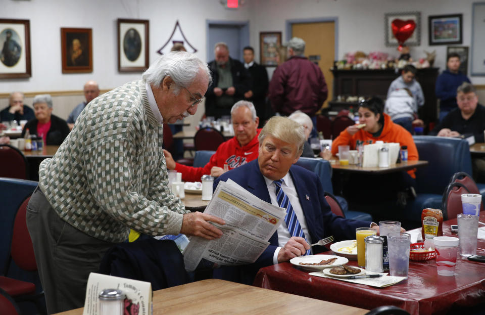 FILE - Republican presidential candidate Donald Trump looks at a newspaper with a diner at Tommy's Country Ham House, Tuesday, Feb. 16, 2016, in Greenville, S.C. For decades, Tommy’s Country Ham House has hosted presidential candidates testing their mettle among voters in South Carolina. But the Greenville landmark has announced that it is turning off the fryer and shutting its doors. Owner Tommy Stevenson announced Sunday, Jan. 31, 2021 that Tommy’s would close this spring. (AP Photo/Paul Sancya, file)