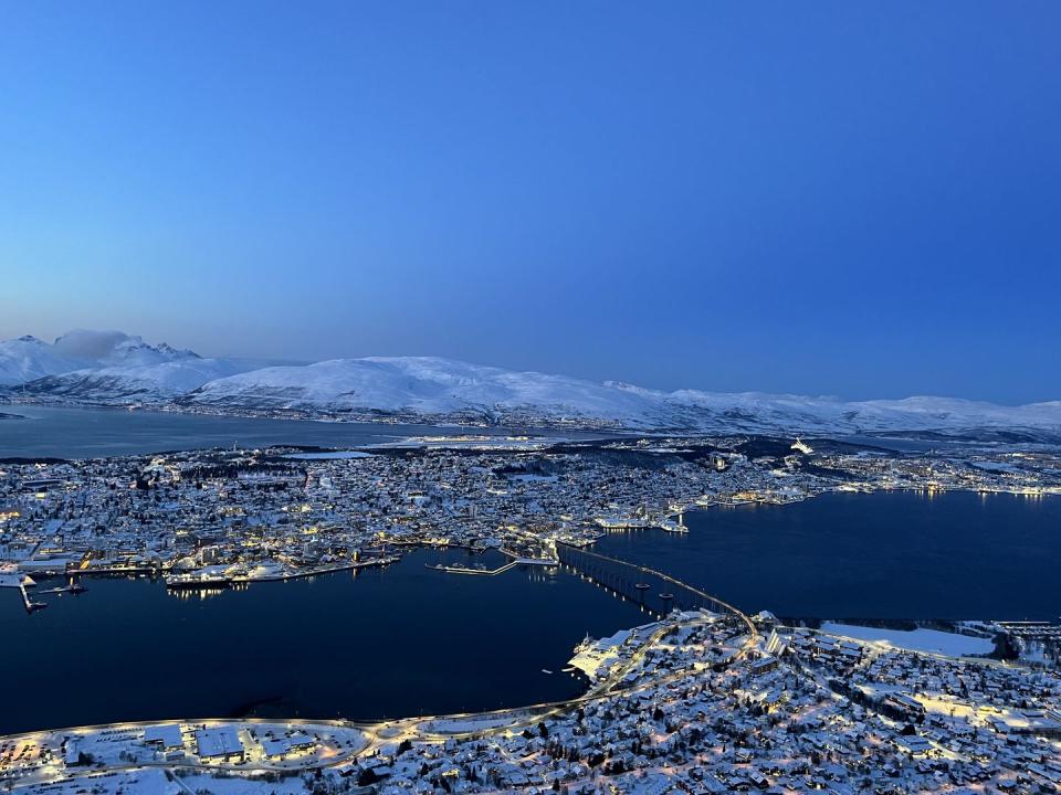 a city next to a body of water with snow on the mountains