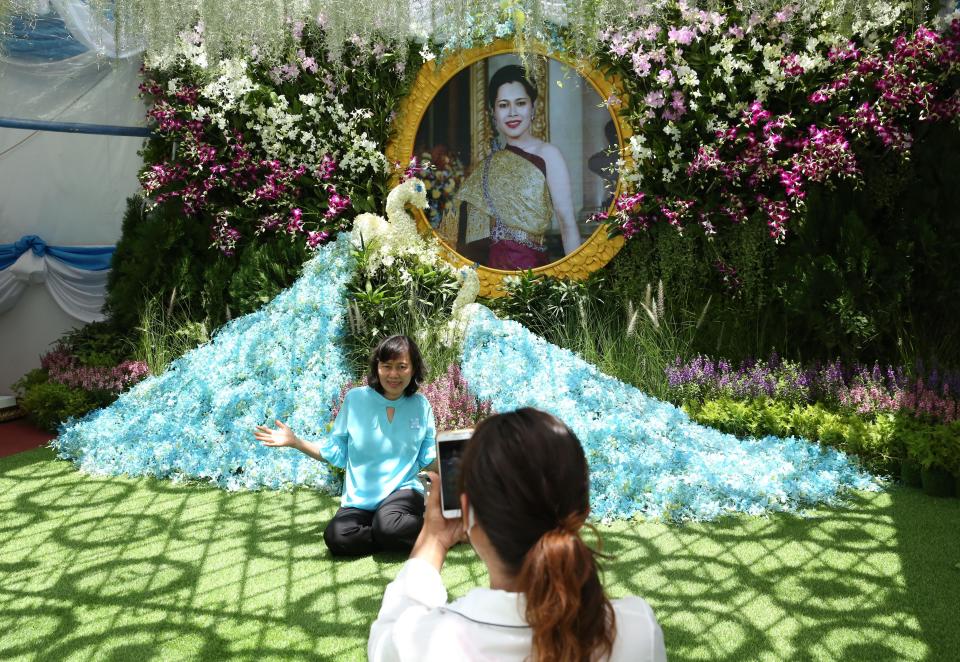 A woman poses for photos in front of the portrait of Queen Sirikit at Sanam Luang during Queen Mother Sirikit's 88th birthday celebrations on August 12, 2020 in Bangkok, Thailand. The queen's birthday is the same day as Mother's Day. / Credit: Wang Guoan/China News Service via Getty Images