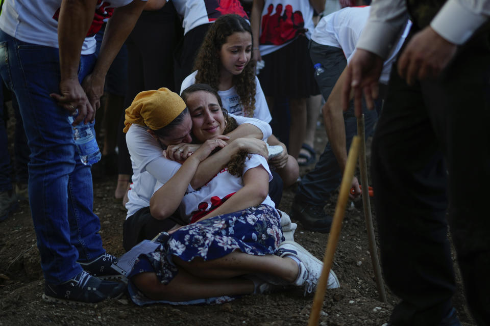 Mourners gather around the graves of British-Israelis Lianne Sharabi and her two daughters, Noiya,16, and Yahel,13, during their funeral in Kfar Harif, Israel, Wednesday, Oct. 25, 2023. Lianne Sharabi and her two daughters were killed by Hamas militants on Oct. 7 in Kibbutz Be'eri near the border with the Gaza Strip. More than 1,400 people were killed and some 200 captured in an unprecedented, multi-front attack by the militant group that rules Gaza. (AP Photo/Ariel Schalit)