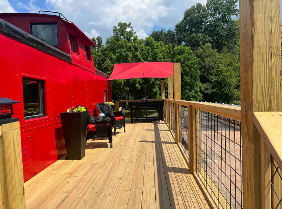 The 1933 Little Red Caboose Airbnb sits on two riverfront acres with stunning mountain and valley views.