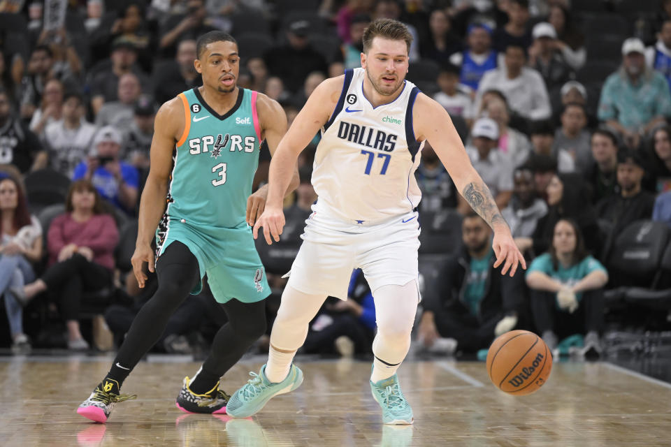 Dallas Mavericks' Luka Doncic (77) reaches for the ball next to San Antonio Spurs' Keldon Johnson during the second half of an NBA basketball game Saturday, Dec. 31, 2022, in San Antonio. (AP Photo/Darren Abate)